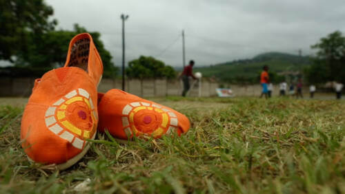 Pair of TOMS shoes with CTAOP branding on soccer field