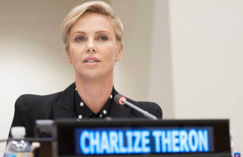 Charlize Theron sitting with microphone giving speech at UN