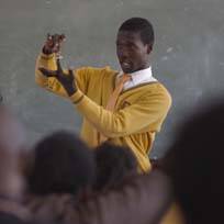 A young man in a yellow sweater leading a classroom lesson