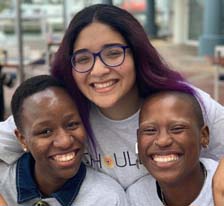 three smiling young people wearing Youth Leadership Scholars t-shirts