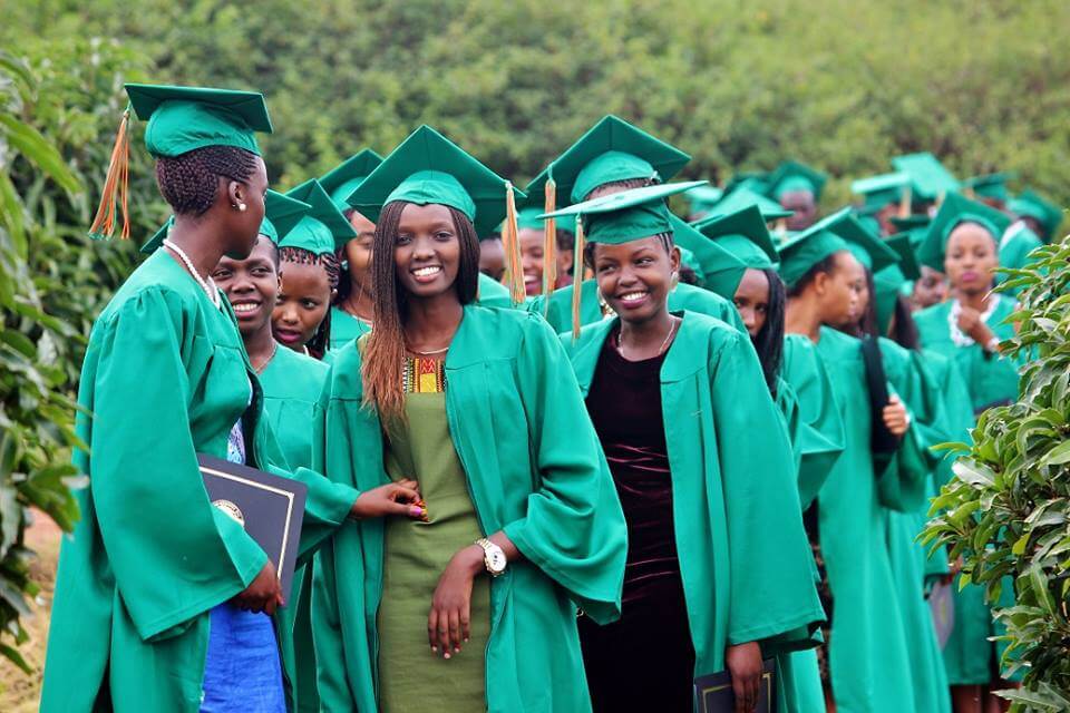 Group of smiling young people in green graduation gowns