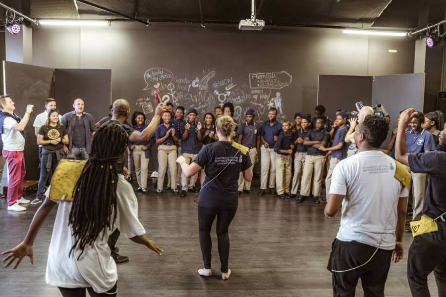 Young people standing in a circle acting out a scene.