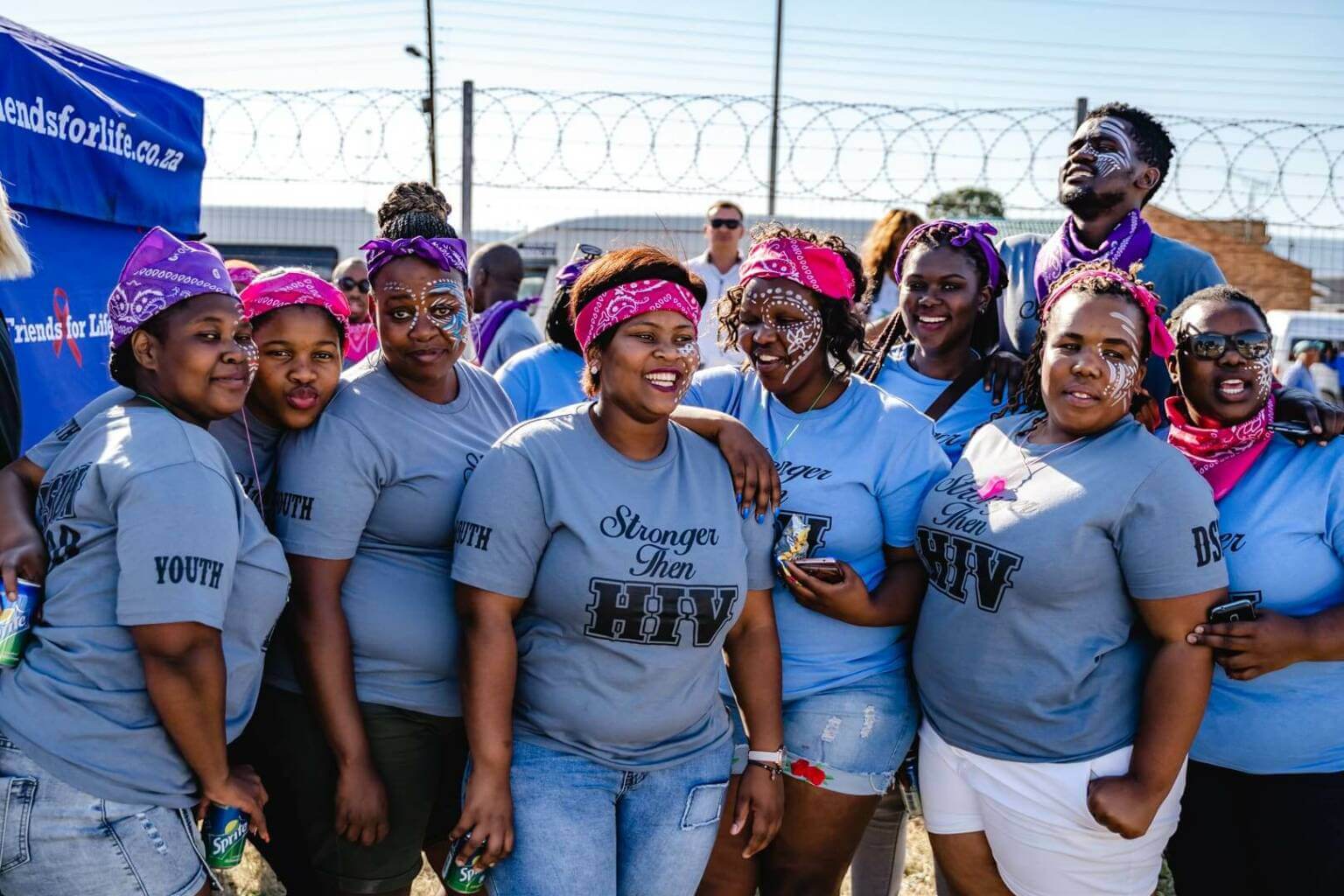 Group of smiling women in blue shirts that read, "Stronger than HIV"