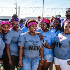 Group of smiling women in blue shirts that read, "Stronger than HIV"