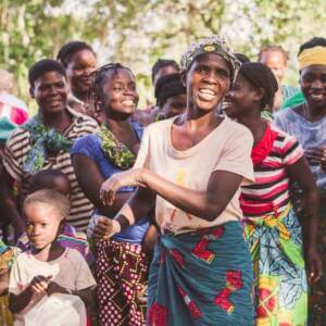 African woman smiling and dancing with a group of smiling people