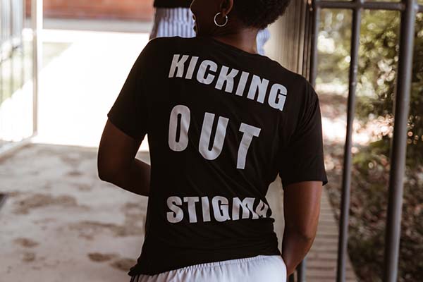 Woman wearing a black shirt that reads "Kicking Out Stigma" on the back