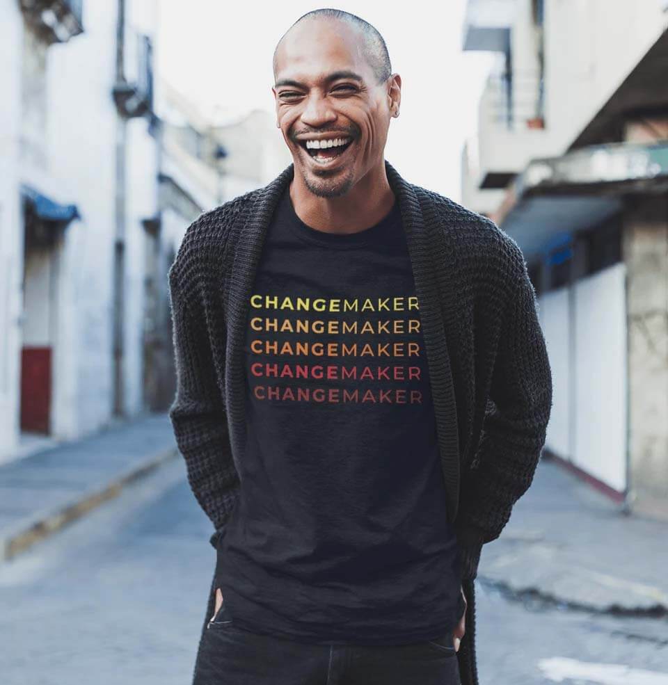 Man wearing a black t-shirt with the word "Changemaker" repeating in yellow, orange, and red