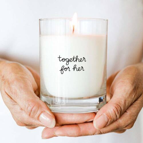 hands holding a candle with the words "together for her" on it