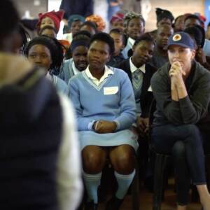 Actor Charlize Theron listening intently to a student presentation