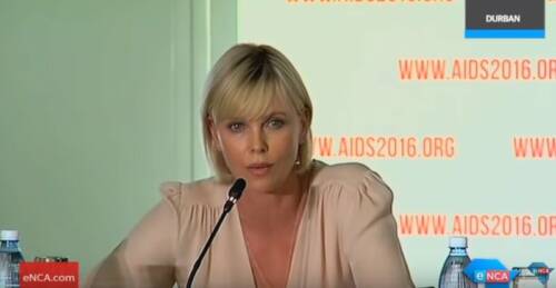 Charlize Theron sitting at microphone
